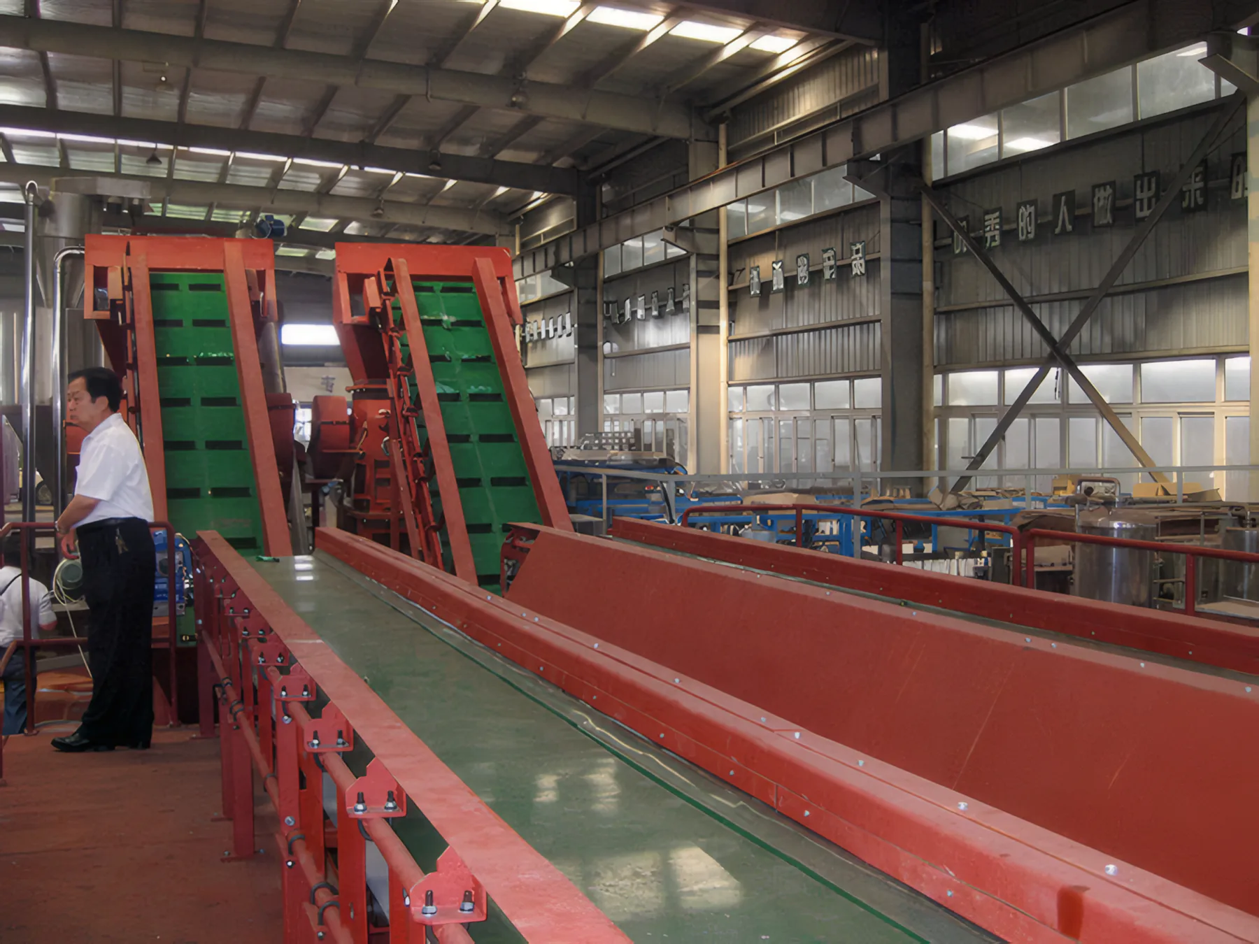 Operator beside the green conveyors and long washing trough