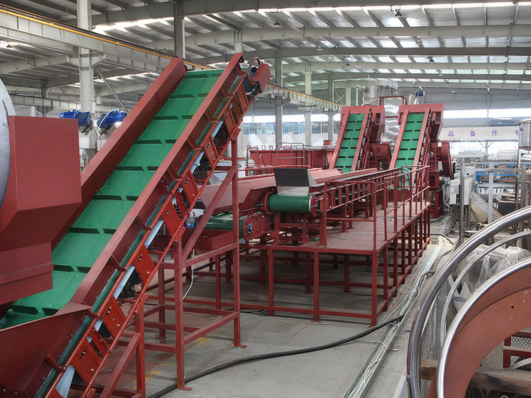 Green belt conveyor rising on a red steel frame